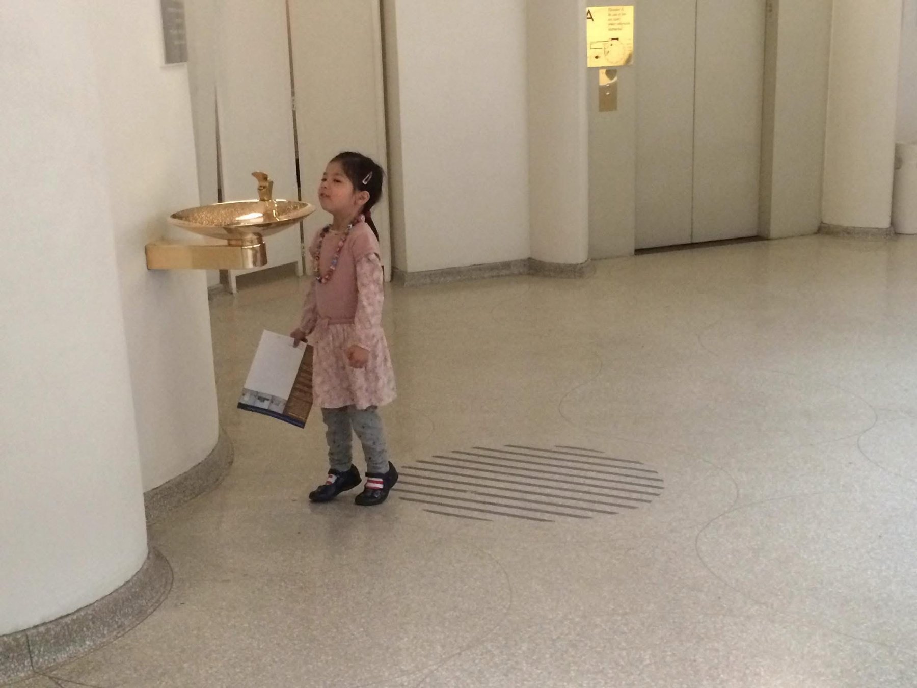 Una niña pequeña frente a un gran bebedero en el interior del museo Guggenheim de Nueva York.